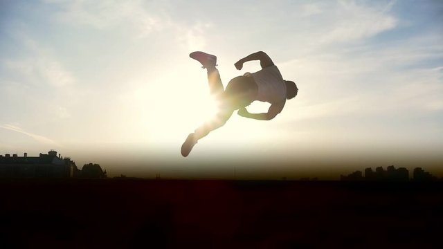 Man Parkour tricker jumper performs amazing flips, silhouette