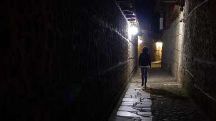 Lonely woman walk in old stone pavement alley at night in the back street
