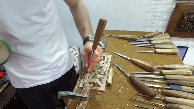 Hands of craftsman carve with a gouge