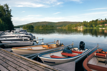 Boats at rest on a lake in the evening. Forest at the background.