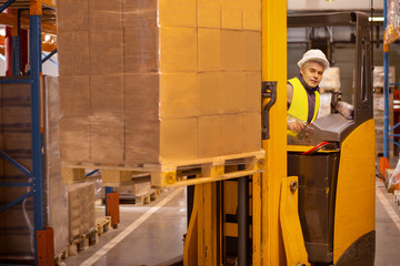 Delivery system. Nice smart man driving the machine vehicle while working in the storehouse