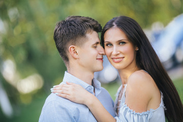Fototapeta premium Happy loving couple stay and hugging at park background lake. Young couple that is about to kiss. Summer sunny day.