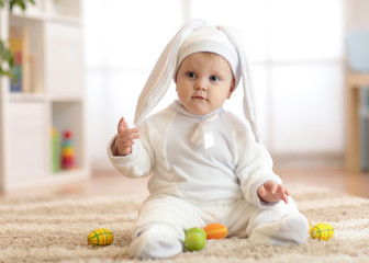 Funny cute baby child in rabbit costume sittng on froor in nursery