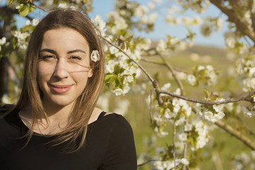 Smiling girl looking at the camera. Cherry trees are in the background.