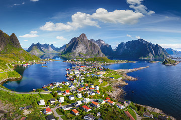 Reine, Lofoten, Norway. The village of Reine under a sunny, blue sky, with the typical rorbu houses. View from the top - obrazy, fototapety, plakaty