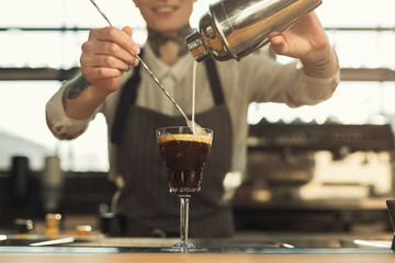 Fototapeta na wymiar Happy barista making coffee cocktail at cafe counter