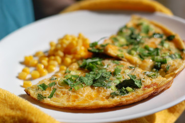fried eggs with tomatoes, onions and parsley and corn