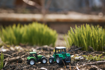 toy tractor on green grass background . Spring sowing works