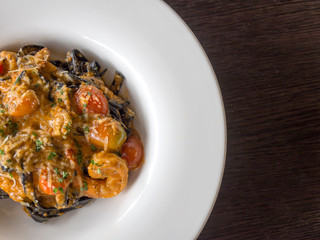 Black Spaghetti in tomato sauce with shrimp, tomato sprinkle with spices and cheese on white plate.Fresh and clean dishes look delicious and yummy