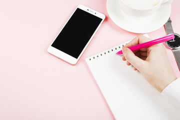 Woman writes in notebook. Concept morning planning (cappuccino, notebook, pen, phone). Copy space