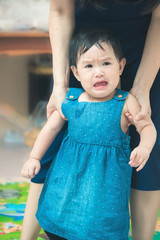 asia mother supports her cute baby to walk with her help