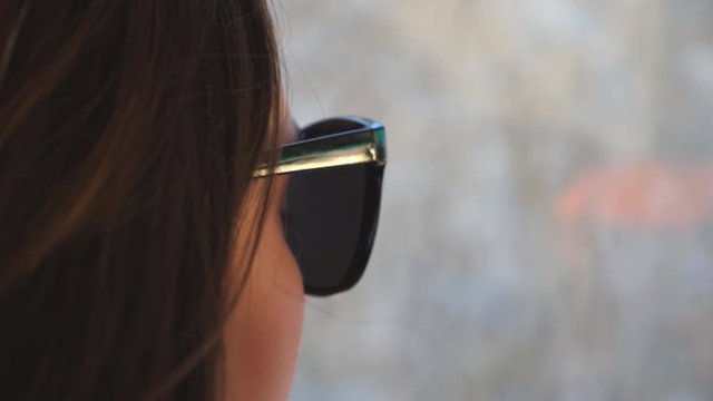 Profile of young woman traveling by bus and looking to window. Girl in sunglasses watching out the window during trip. Female tourist takes a autobus ride. Vacation or excursion concept. Close up