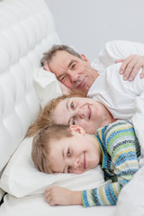 Fototapeta na wymiar Happy young boy with his grandparents on the bed