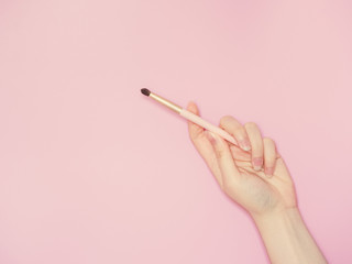 cosmetic and beauty concept from beauty asian hand hold and use cosmetic brush with isolated pink pastel background
