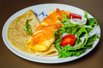 Florentine omelet with salmon, cream cheese and spinach on a white plate