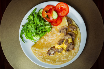 Scrambled eggs with mozzarella and champignon mushrooms on a white plate