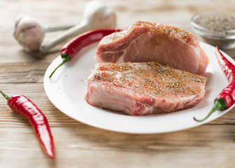 Raw pork ribs with red pepper, garlic and seasonings on a wooden background.