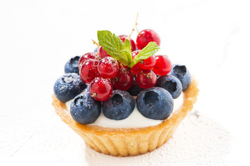 mini tart with cream and berries on white background