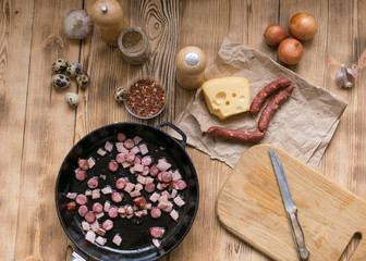Bavarian sausages are sliced and fried in a frying pan.