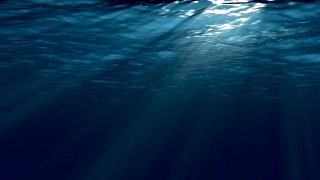 Dark blue sea surface seen from underwater. 
Abstract waves underwater and rays of sunlight shining through. 
