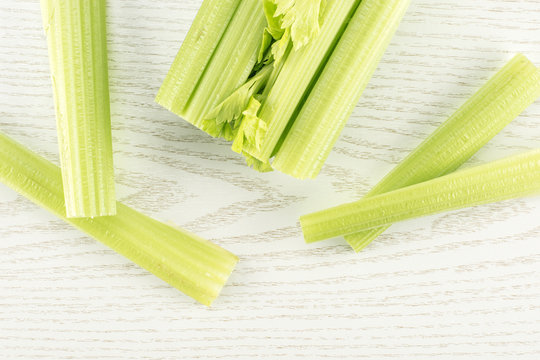One fresh green celery with four sticks isolated on light wooden background.