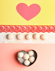 Red heart shaped box with sweets, coconut balls, top view.