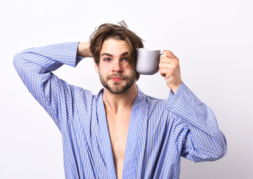 Man with beard in blue dressing gown on grey background.