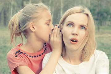 The daughter tells secrets to the mother's ear. Toned.