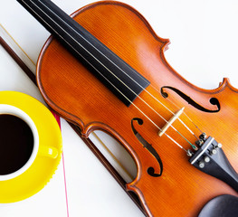 Fototapeta premium The classic violin and bow put beside half of yellow ceramic coffee cup