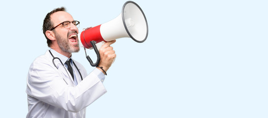 Doctor senior man, medical professional communicates shouting loud holding a megaphone, expressing...