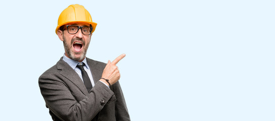Senior architect or engineer pointing away side with finger isolated over blue background