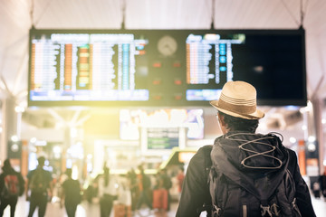 young traveler or tourist looking at airport time board for flight schedule, travel, holiday, tourism and holiday concept