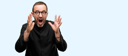 Fototapeta premium Priest religion man stressful keeping hands on head, terrified in panic, shouting isolated over blue background