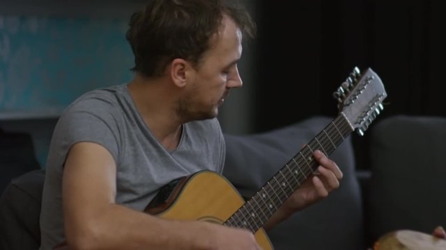 Medium shot of man singing playing guitar as cheerful woman accompanying him on ethnic drums