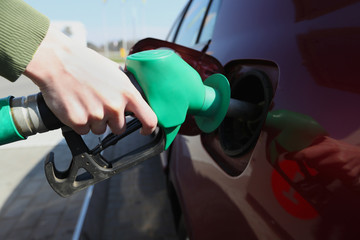 Woman filling her car with petrol at gas statiion