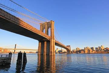 Fototapeta premium Brooklyn Bridge over East River with view of New York City Lower Manhattan, waterfront at twilight, USA