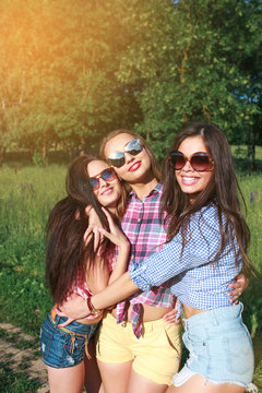 Happy friends in the park on a sunny day . Summer lifestyle portrait of three hipster women enjoy nice day, wearing bright sunglasses. Best friends girls having fun,