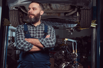 Fototapeta na wymiar Two bearded brutal mechanics repair a car on a lift in the garage. 