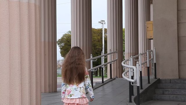 Young girl walking up ramp at airport with pillars in background