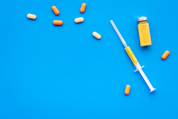 Medical therapy. Syringe, bottle with drug, pills on blue background top view copy space