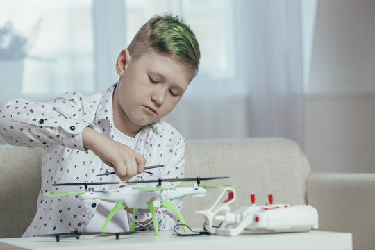 Confident boy adjusting drone on coffee table while sitting at home