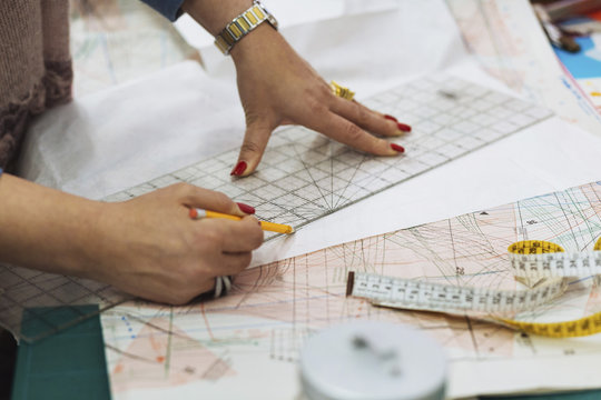 Cropped image of fashion designer marking on fabric at workshop