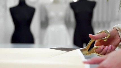 Beautiful fashion designer girl cut out on paper with gold scissors patterns for fabric on mannequins background dressed in wedding dresses. Manufacturer of wedding dresses.