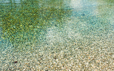 Abstraction of spring water,Italy,24 April 2018,spring water, clear surface with mountain pebbles,background wallpaper texture
