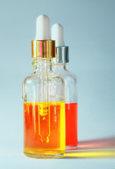 two bubbles of useful cosmetic oil in transparent glass bottles on bright background