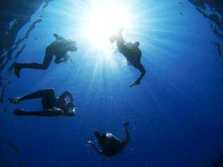 Under view of the sea and four joyful friends swimming and relaxing for summer holidays.