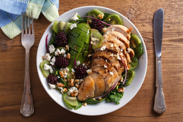 Kiwi blackberry balsamic chicken salad with avocado, spinach, feta cheese and walnuts. View from above, top