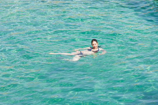Cala Murada, Mallorca - A young woman smiling while swimming in the turquoise Mediterranean Sea at Cala Murada