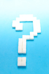 Refined sugar in the form of question mark on blue background.
