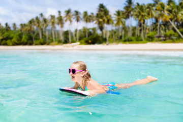 Kids surf on tropical beach. Vacation with child.